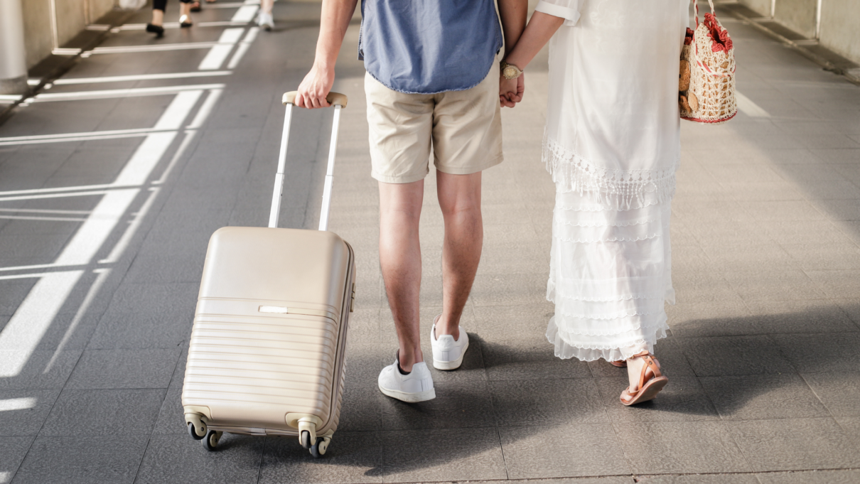 man and woman walking with suitcase