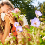 Girl in field of flowers blowing her nose in a tissue